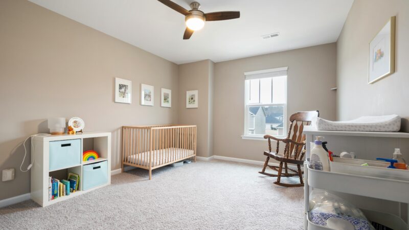 Bright, minimalist children's room with a crib, rocking chair, and organized storage unit.